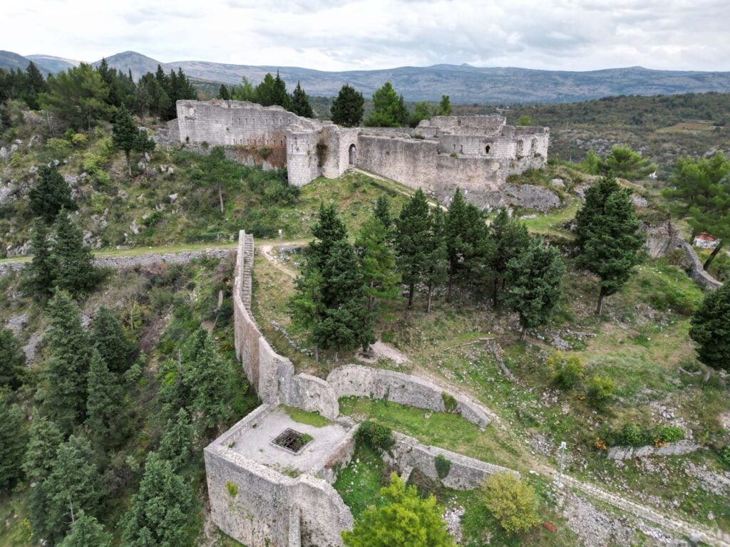 Verdwenen kastelen op een heuvel met omringend groene natuur en bos.